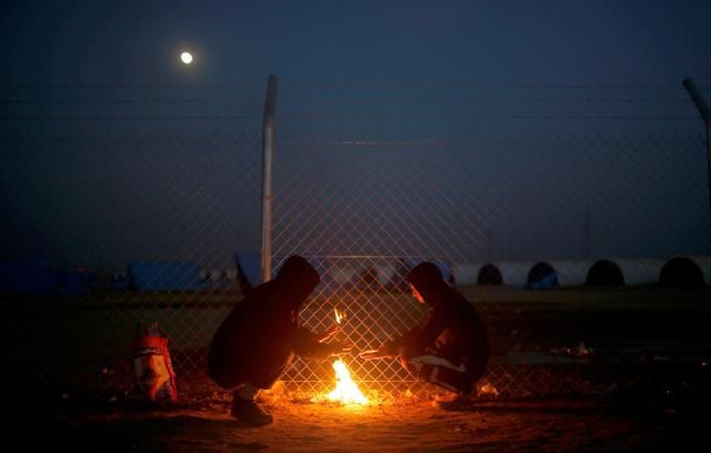 Displaced Iraqi who fled the Islamic State stronghold of Mosul, warm themselves by a fire at Khazer camp, Iraq. (REUTERS) Displaced Iraqi who fled the Islamic State stronghold of Mosul, warm themselves by a fire at Khazer camp, Iraq. (REUTERS)