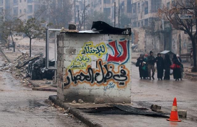 People carry their belongings as they flee deeper into the remaining rebel-held areas of Aleppo. The Arabic words read, "No to monopolising commodities and raising prices under the siege". (Reuters) People carry their belongings as they flee deeper into the remaining rebel-held areas of Aleppo. The Arabic words read, "No to monopolising commodities and raising prices under the siege". (Reuters)