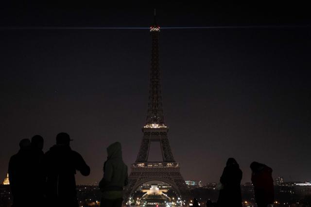 People look at the lights of the Eiffel Tower, which were switched off, in Paris. (AFP Photo)
