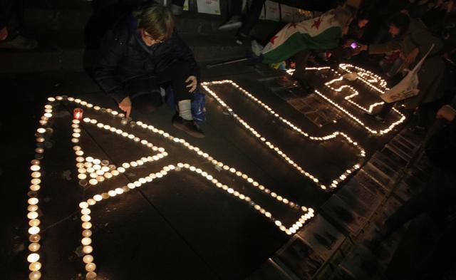 A man kneels at candles reading Aleppo during a gathering in a show of support for Syrians. (AP Photo)