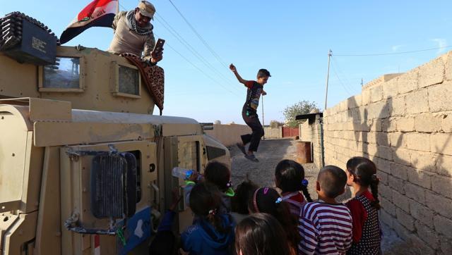 Children gather next to an Iraqi forces vehicle patrolling a street in the village of Jarif, some 45 kilometres south of Mosul, on November 12, 2016, after retaking it from Islamic State (IS) group jihadists. (AFP File Photo)