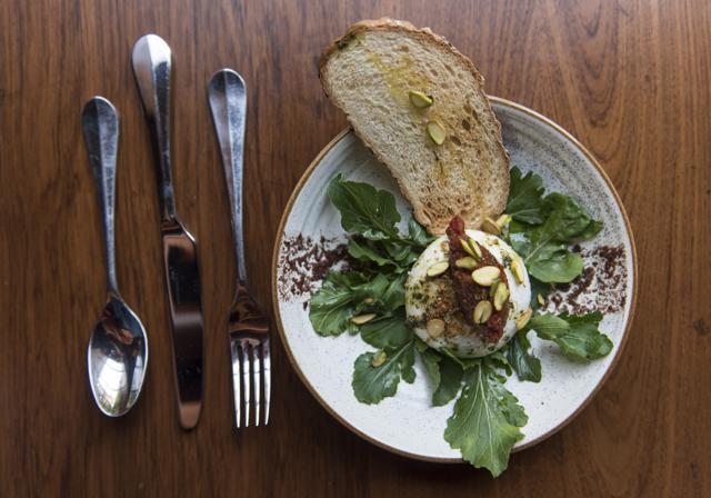 Baked burrata served with a dressing of arugula leaves, filled with thick cream cheese and tempered with the sharp sweetness of a tomato-thyme chutney topping, is a tasty treat.