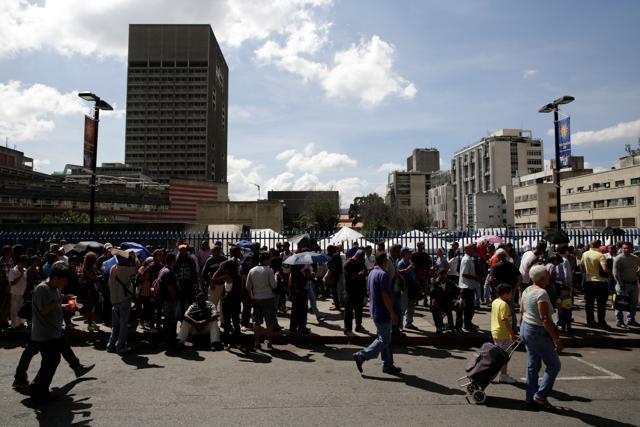 People queue to deposit their 100 bolivar notes. (Reuters Photo) People queue to deposit their 100 bolivar notes. (Reuters Photo)