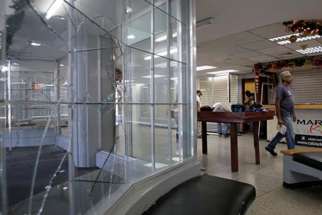 People walk next to broken showcases after a shoe shop was looted in Maracaibo, Venezuela. (Reuters Photo) People walk next to broken showcases after a shoe shop was looted in Maracaibo, Venezuela. (Reuters Photo)