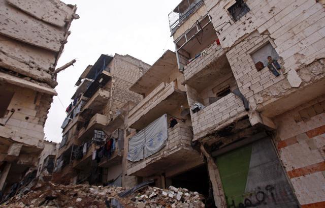 Residents in a government-held part of Aleppo's Salaheddin neighbourhood look out from the balconies of their damaged houses at the road. (AFP Photo)