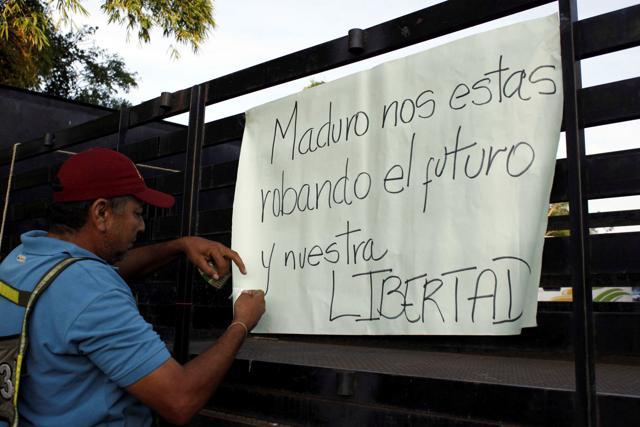 A man places a placard on a truck, which reads: ‘Maduro, you're stealing our future and our freedom’, during a protest due to a lack of cash in El Pinal, Venezuela. (Reuters Photo) A man places a placard on a truck, which reads: ‘Maduro, you're stealing our future and our freedom’, during a protest due to a lack of cash in El Pinal, Venezuela. (Reuters Photo)