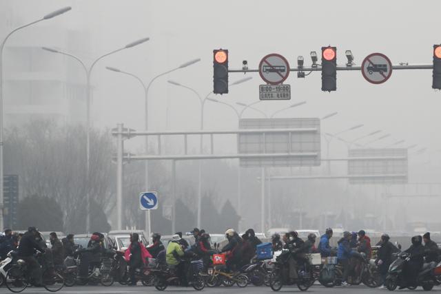 People ride bicycles and electric bikes in Beijing as the city is shrouded by heavy smog on Tuesday. (AP photo) People ride bicycles and electric bikes in Beijing as the city is shrouded by heavy smog on Tuesday. (AP photo)