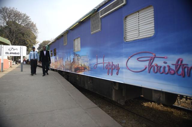 Pakistan railway employees walk past a Christmas-themed train . (AFP) Pakistan railway employees walk past a Christmas-themed train . (AFP)