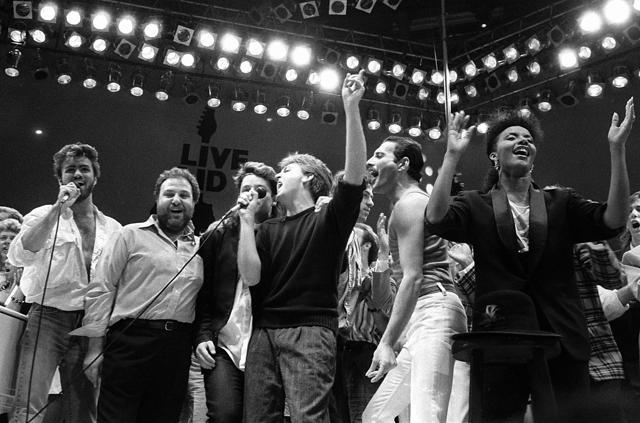 In this July 13, 1985, file photo, from left, George Michael of Wham!, concert promoter Harvey Goldsmith, Bono of U2, Paul McCartney, concert organizer Bob Geldof and Freddie Mercury of Queen join in the finale of the Live Aid famine relief concert, at Wembley Stadium, London. (AP Photo) In this July 13, 1985, file photo, from left, George Michael of Wham!, concert promoter Harvey Goldsmith, Bono of U2, Paul McCartney, concert organizer Bob Geldof and Freddie Mercury of Queen join in the finale of the Live Aid famine relief concert, at Wembley Stadium, London. (AP Photo)