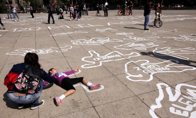 A girl lies on a silhouette that represents a victim of violence that was painted by an activist of the organization Nos hacen falta (We are missing them), during a demonstration demanding justice for the victims of violence and drugs, at the Monument to the Revolution in Mexico City in Mexico on December 11, 2016. The names of victims are seen in each silhouette. (Reuters) A girl lies on a silhouette that represents a victim of violence that was painted by an activist of the organization Nos hacen falta (We are missing them), during a demonstration demanding justice for the victims of violence and drugs, at the Monument to the Revolution in Mexico City in Mexico on December 11, 2016. The names of victims are seen in each silhouette. (Reuters)