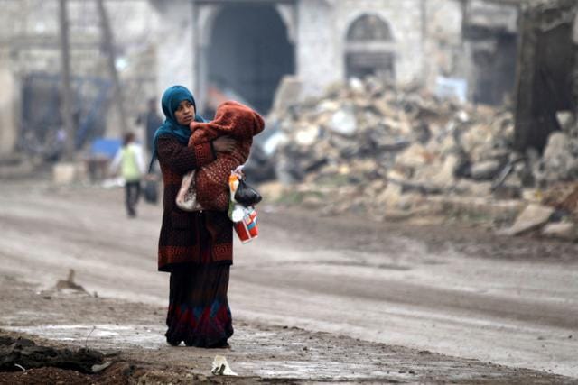 A woman carries a child as she walks near rubble of damaged buildings in al-Rai town, northern Aleppo. (Reuters Photo) A woman carries a child as she walks near rubble of damaged buildings in al-Rai town, northern Aleppo. (Reuters Photo)