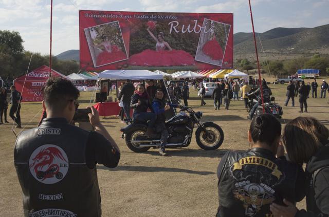 A couple, who travelled from Mexico City with a group of bikers, pose with a banner welcoming visitors to Rubi's down-home 15th birthday party in La Joya. They were among the thousands who responded to the open invitation to Rubi Ibarra’s birthday. (AP)