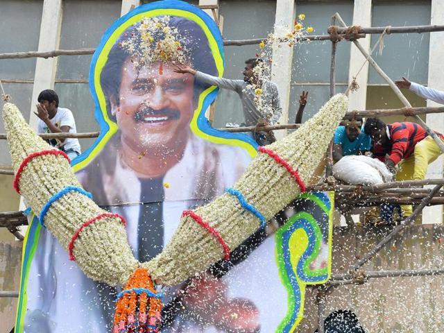Fans shower flower petals on a cut-out board image of Rajinikanth on the facade of a movie theatre on the first day of release of his film Kabali in Bangalore on July 22, 2016. (AFP) Fans shower flower petals on a cut-out board image of Rajinikanth on the facade of a movie theatre on the first day of release of his film Kabali in Bangalore on July 22, 2016. (AFP)
