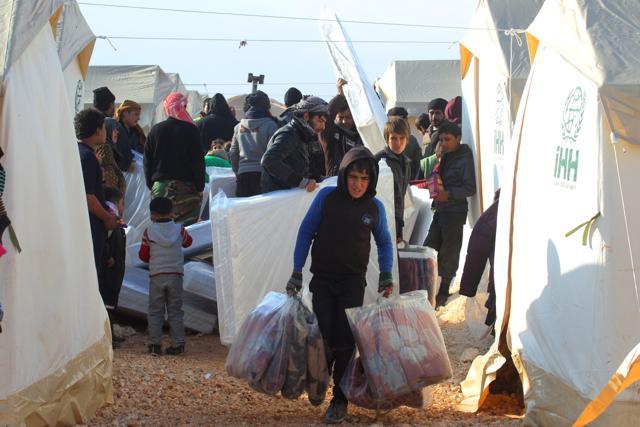 A boy, evacuee from a rebel-held area of Aleppo, carries blankets received as aid in al-Kamouneh camp, Idlib province, Syria. (Reuters photo) A boy, evacuee from a rebel-held area of Aleppo, carries blankets received as aid in al-Kamouneh camp, Idlib province, Syria. (Reuters photo)