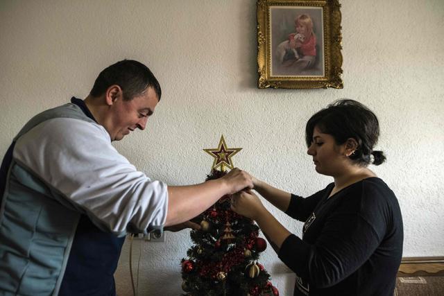 Noora Arkavazi (R) and her husband Bobi Dodevski decorate a Christmas tree in their home in Kumanovo on December 21, 2016. (AFP Photo)