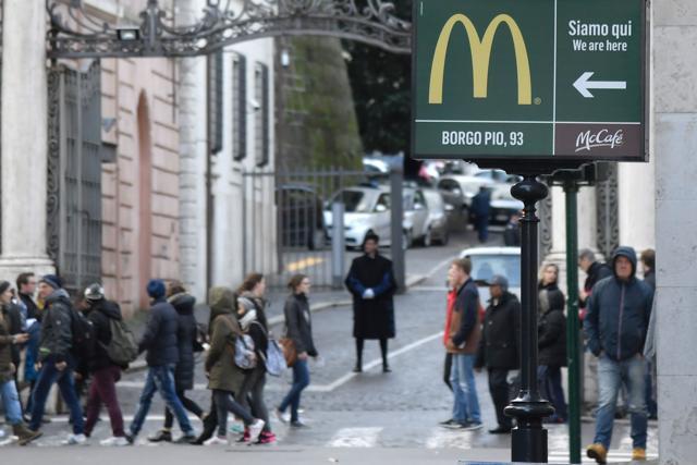 A sign showing the direction of a McDonald restaurant is seen near an entrance of the Vatican in the background, in Rome. (AFP Photo) A sign showing the direction of a McDonald restaurant is seen near an entrance of the Vatican in the background, in Rome. (AFP Photo)