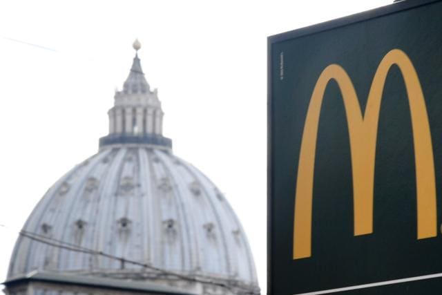 A sign showing the direction of a McDonald restaurant is seen with the cupola of St Peter's basilica. (AFP Photo) A sign showing the direction of a McDonald restaurant is seen with the cupola of St Peter's basilica. (AFP Photo)