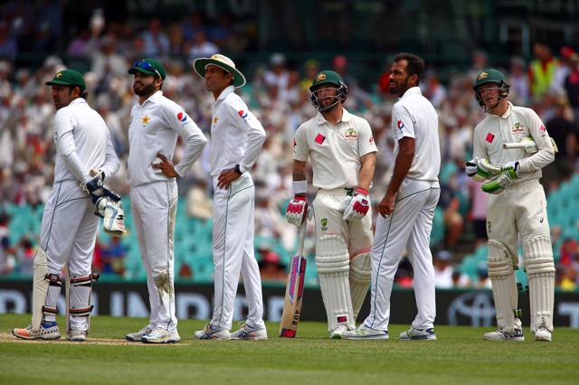 Australia's Peter Handscomb (R) watches with teammate Matthew Wade and members of the Pakistan team as a replay shows he hit his wicket in the Syndey Test (REUTERS)