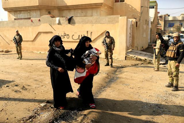 A displaced Iraqi woman, who fled the Islamic State stronghold of Mosul, carries her baby in the Mithaq district of eastern Mosul on Wednesday. (Reuters) A displaced Iraqi woman, who fled the Islamic State stronghold of Mosul, carries her baby in the Mithaq district of eastern Mosul on Wednesday. (Reuters)