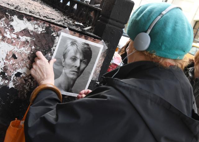 A woman tapes a David Bowie picture on a wall outside of his SoHo apartment building on the first anniversary of Bowie's death on January 10, 2017 in New York City. (AFP)
