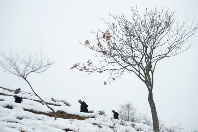 Kashmiri villagers walk along a snow-covered road on the outskirts of Srinagar on January 13, 2017. A cold wave further tightened its grip in Jammu and Kashmir with most places in the state recording sub-zero temperatures. (AFP)