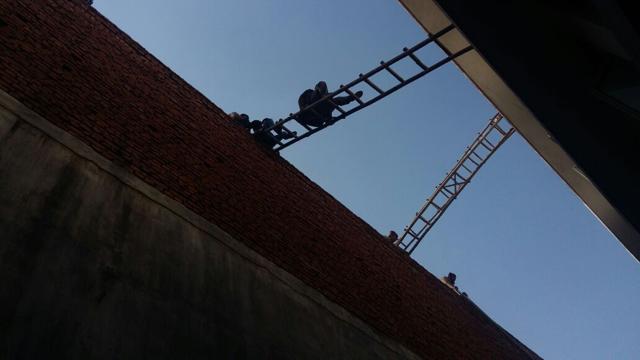 Firefighters used ladders to create a bridge between two buildings to evacuate 60 labourers trapped on the second floor (HT Photo) Firefighters used ladders to create a bridge between two buildings to evacuate 60 labourers trapped on the second floor (HT Photo)