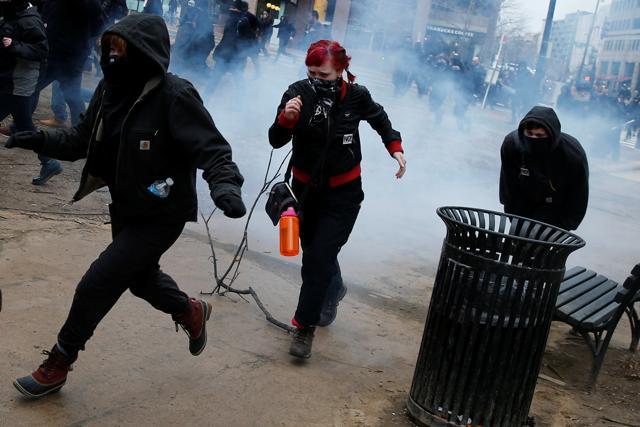 Activists run after being hit by a stun grenade while protesting against US President Donald Trump on the sidelines of the inauguration in Washington, DC. (REUTERS)