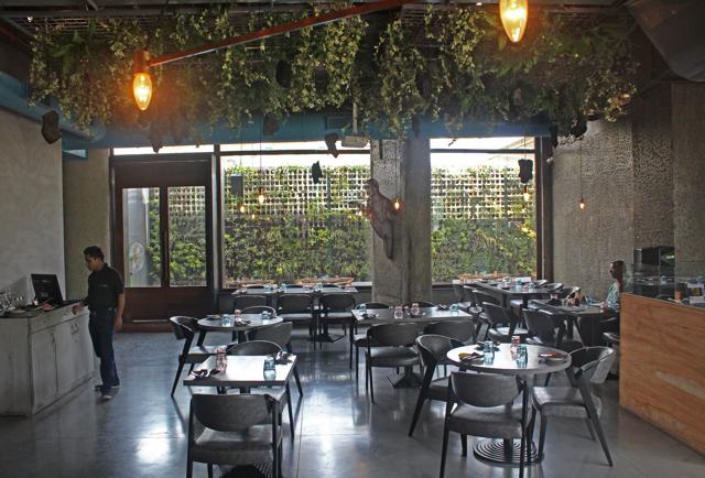 The restaurant is swathed in natural materials and textures: stone and wood on the floors and potted plants suspended from the ceiling of a cool French-windowed dining room. (Satyabrata Tripathy/ HT Photo)