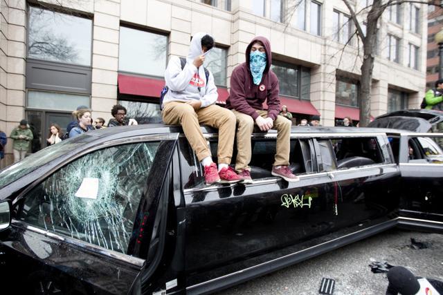 Demonstrators sit at the top of a limousine with the windows broken during the demonstration downtown Washington Friday, Jan. 20, 2017, during the inauguration of President Donald Trump. ( AP Photo/Jose Luis Magana) (AP)