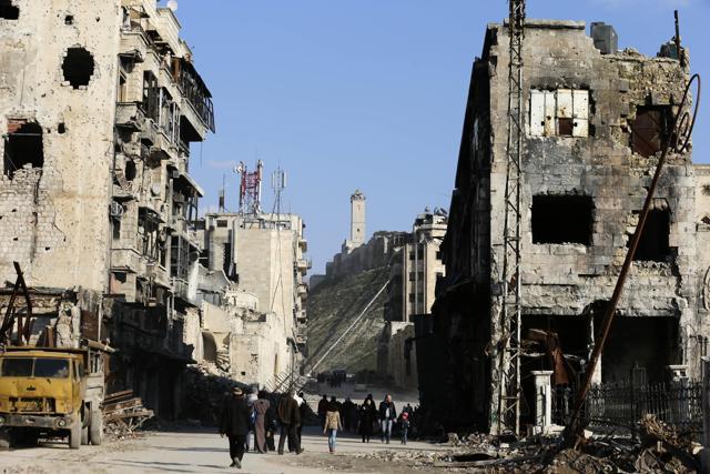 Residents walk through damaged buildings near to the ancient Aleppo Citadel. (AP Photo) Residents walk through damaged buildings near to the ancient Aleppo Citadel. (AP Photo)