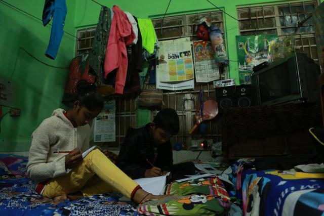 Siblings go about their studies in their dimly lit room. (AmalKS/HTPHOTO)