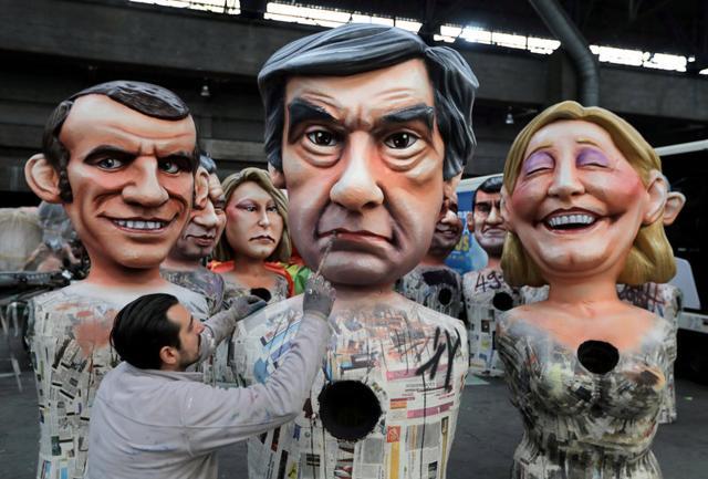 A worker puts the final touches to a giant figure of Francois Fillon (centre), former French prime minister, member of The Republicans political party and 2017 presidential candidate of the French centre-right, next to French National Front leader Marine Le Pen (right) and Emmanuel Macron (left), head of the political movement En Marche !. (Reuters File Photo)