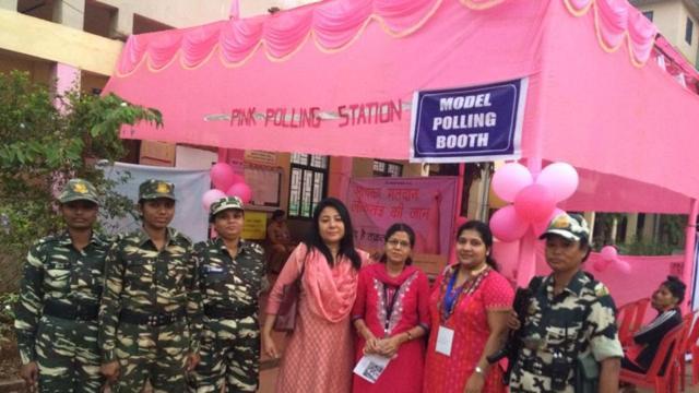 Polling officials and security forces pose outside a model pink polling booth in Panaji, Goa. (Nida Khan/HT Photo)