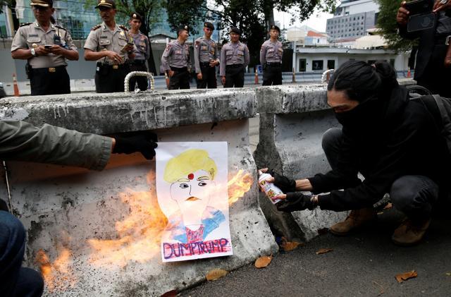 An activist burns a poster depicting Trump as they protest his recent policies, outside the US embassy in Jakarta, on Saturday. (REUTERS) An activist burns a poster depicting Trump as they protest his recent policies, outside the US embassy in Jakarta, on Saturday. (REUTERS)
