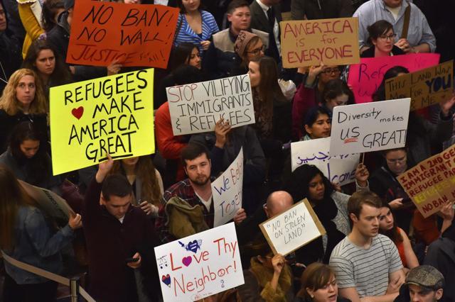 People hold up signs during a protest against Trump's immigration rules at the Regan National Airport in Arlington, Virginia. (AFP) People hold up signs during a protest against Trump's immigration rules at the Regan National Airport in Arlington, Virginia. (AFP)