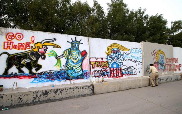 An Iraqi graffiti artist sprays a cement wall with anti-US President Donald Trump slogans in the southern Iraqi city of Basra. (AFP Photo) An Iraqi graffiti artist sprays a cement wall with anti-US President Donald Trump slogans in the southern Iraqi city of Basra. (AFP Photo)