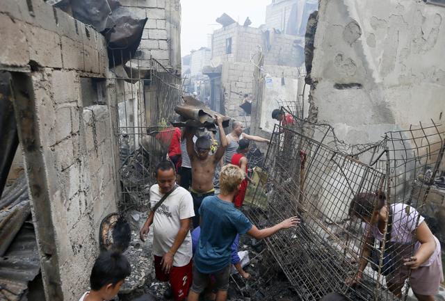 Fire victims sift through the debris following the overnight fire. (AP Photo) Fire victims sift through the debris following the overnight fire. (AP Photo)