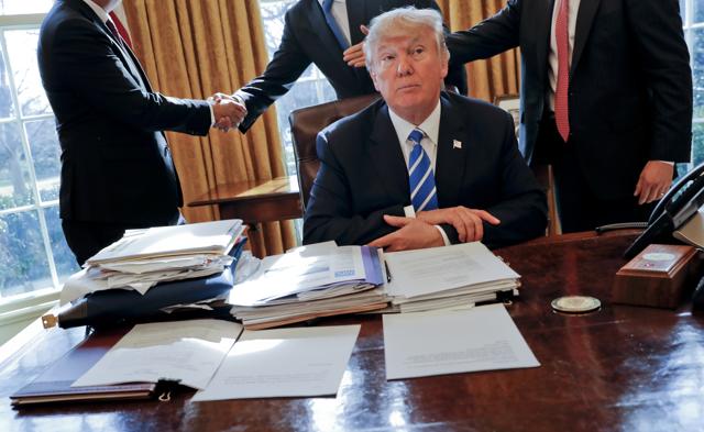 President Donald Trump sits at his desk after a meeting with Intel CEO Brian Krzanich, left, and members of his staff in the Oval Office of the White House in Washington. (AP Photo) President Donald Trump sits at his desk after a meeting with Intel CEO Brian Krzanich, left, and members of his staff in the Oval Office of the White House in Washington. (AP Photo)