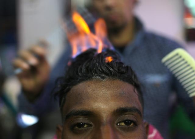 Palestinian barber Ramadan Odwan styles and straightens the hair of a customer. (Reuters Photo)