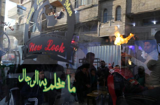 Palestinian barber Ramadan Odwan is pictured through a glass window at his salon in Rafah. (Reuters Photo)