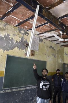 A teacher points to a hanging tubelight from the plaster-less ceiling of the Government Girls/Boys Senior Secondary School at Shahbad Dairy. The school building was declared dangerous last year. (Sushil Kumar/HT Photo) A teacher points to a hanging tubelight from the plaster-less ceiling of the Government Girls/Boys Senior Secondary School at Shahbad Dairy. The school building was declared dangerous last year. (Sushil Kumar/HT Photo)
