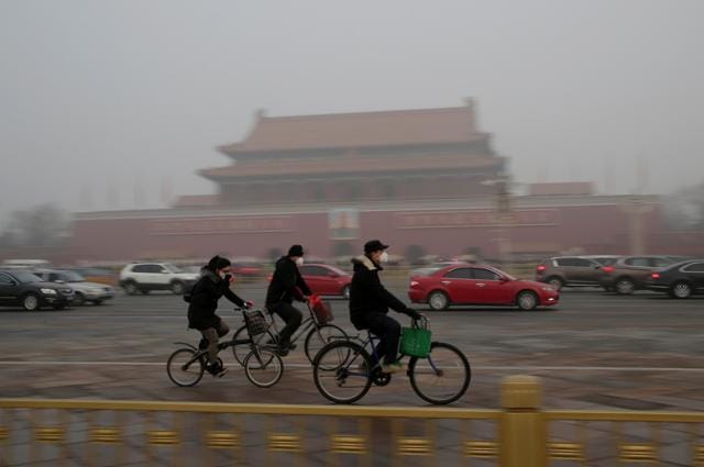 People wearing masks cycle past Tiananmen Gate during smog after a red alert was issued for heavy air pollution in Beijing, China in December, 2016. (Reuters Photo) People wearing masks cycle past Tiananmen Gate during smog after a red alert was issued for heavy air pollution in Beijing, China in December, 2016. (Reuters Photo)