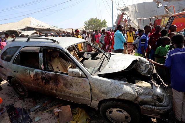 People stand near a car destroyed in the suicide bomb explosion in Mogadishu on Sunday. (REUTERS) People stand near a car destroyed in the suicide bomb explosion in Mogadishu on Sunday. (REUTERS)