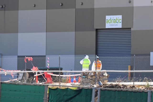 Investigators stand in a cordoned off area after a Beechcraft plane crashed into a shopping centre just after take-off from the Essendon airport in Melbourne on February 21. (AFP)