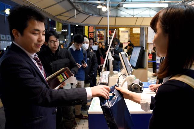A fan of Haruki Murakami buys a copy of his new novel Killing Commendatore at a bookstore in Tokyo in the early hours of February 24, 2017. (AFP)