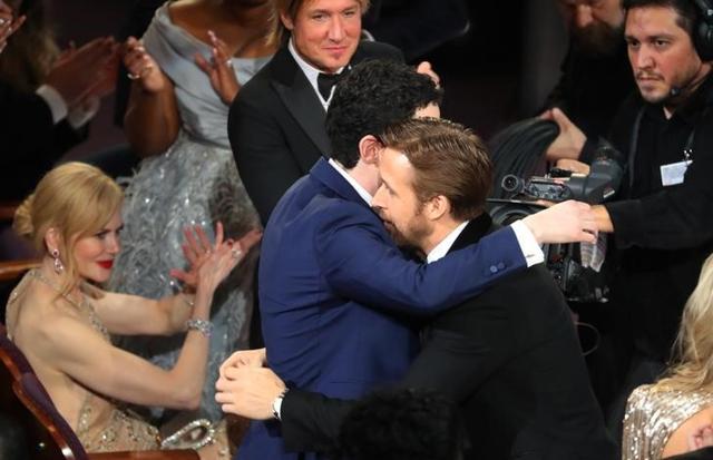 Damien Chazelle (hidden) is congratulated by actor Ryan Gosling (R) for winning Best Director. At left is Nicole Kidman and (C) is her husband Keith Urban. (REUTERS) Damien Chazelle (hidden) is congratulated by actor Ryan Gosling (R) for winning Best Director. At left is Nicole Kidman and (C) is her husband Keith Urban. (REUTERS)