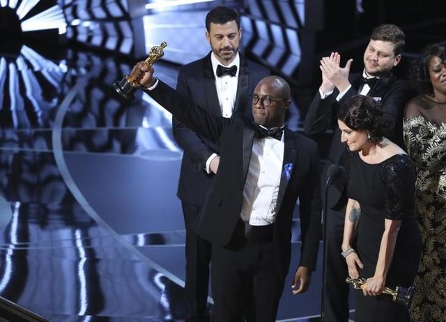 Writer and Director Barry Jenkins of Moonlight holds up the Best Picture Oscar in front of host Jimmy Kimmel (rear) as he stands with Producer Adele Romanski (R). (Reuters) Writer and Director Barry Jenkins of Moonlight holds up the Best Picture Oscar in front of host Jimmy Kimmel (rear) as he stands with Producer Adele Romanski (R). (Reuters)