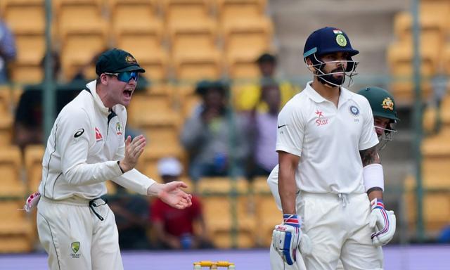 Virat Kohli looks on as Australian captain Steve Smith celebrates his dismissal in Bangalore on Saturday. (PTI) Virat Kohli looks on as Australian captain Steve Smith celebrates his dismissal in Bangalore on Saturday. (PTI)
