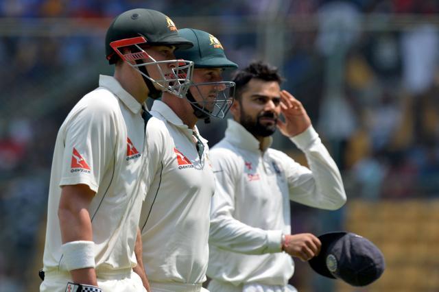 Virat Kohli looks on as Australian batsmen Shaun Marsh (centre) and Matthew Renshaw (left) return to the pavilion for lunch on Day 2 in Bangalore Test on Sunday. (AFP) Virat Kohli looks on as Australian batsmen Shaun Marsh (centre) and Matthew Renshaw (left) return to the pavilion for lunch on Day 2 in Bangalore Test on Sunday. (AFP)