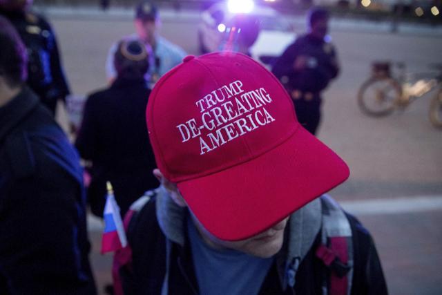 A man wears a hat that reads "Trump De-Greating America" as people gather for a protest against US President Donald Trump's new travel ban at Lafayette Park outside the White House in Washington on March 6, 2017. (AP) A man wears a hat that reads "Trump De-Greating America" as people gather for a protest against US President Donald Trump's new travel ban at Lafayette Park outside the White House in Washington on March 6, 2017. (AP)